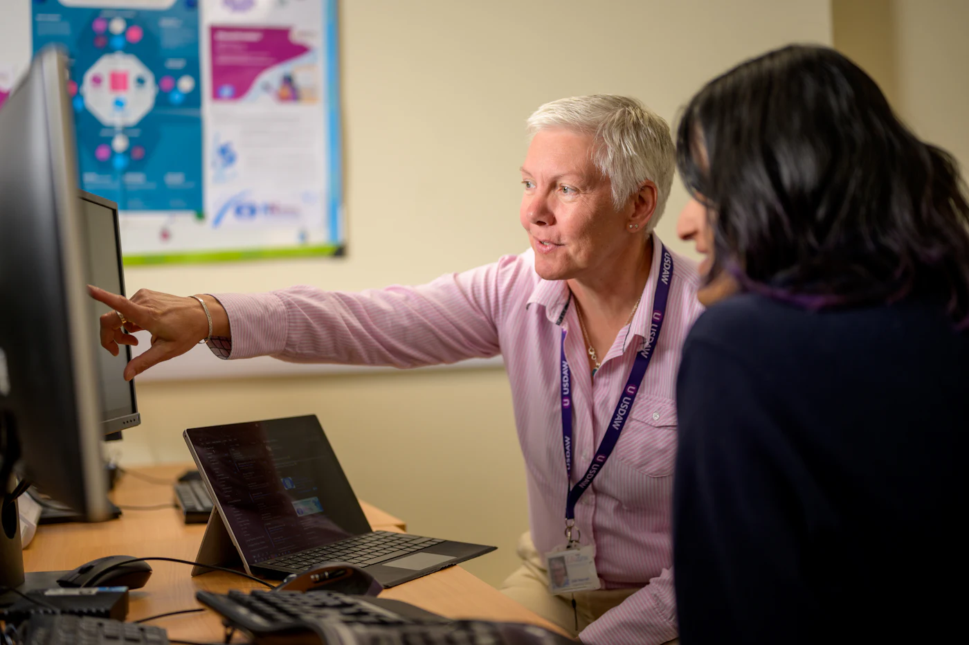 A team lead walking a new colleague through a screen